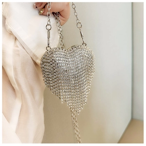 Close-up of silver heart-shaped evening bag with sparkling rhinestones and metal fringes