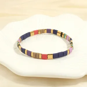 Detail of colorful Bohemian Tila bead stretch bracelet with gold accents on a petal plate