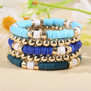Détail de bracelets superposés en perles Heishi bleues et blanches avec accents dorés