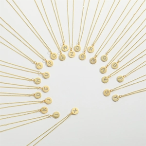 Minimalist gold necklaces with sparkling letter pendants arranged in a circular pattern