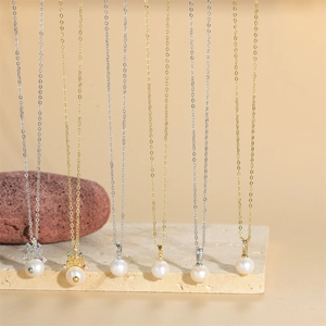 Elegant crown pearl pendant necklaces in gold and silver chains on natural stone base
