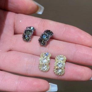 Detalle de pendientes geométricos de lujo con tres cristales verticales en verde y claro