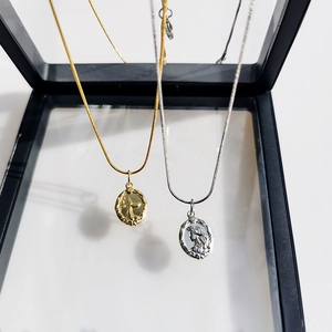Detailed macro view of vintage double-sided mermaid relief necklaces in gold and silver