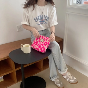 Detailed view of neon pink leopard print zipper pouch held by a model in a casual setting