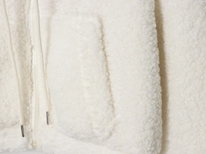 Close-up of white fleece jacket featuring a zipper, drawstrings, and pocket detail