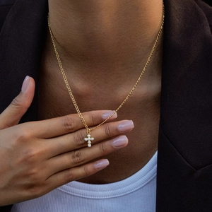 Dettaglio della collana a croce in titanio dorato con perle sul collo, catena Figaro