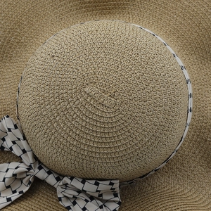 Detalle de textura de paja tejida y cinta geométrica con lazo en sombrero de sol