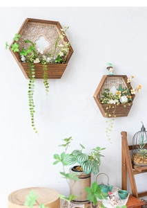 Detalle de dos maceteros hexagonales de madera para pared con celosía retro y flores artificiales