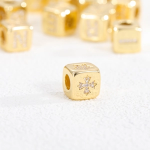Macro shot of 18K gold plated zircon cube beads with cross and letter N patterns