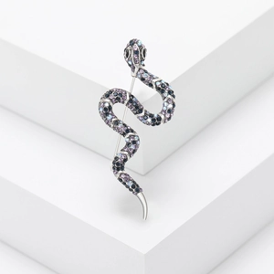 Detail of silver snake brooch with sparkling purple and blue rhinestones on white cubes