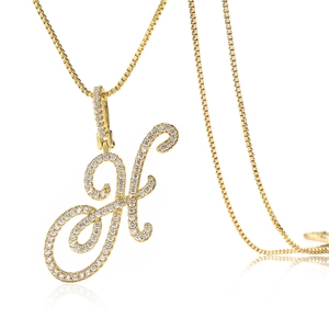 Vue macro du pendentif lettre H doré avec zircons pavés sur une chaîne maille miroir