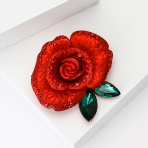 Detailed view of an elegant red enamel rose brooch with sparkling red crystals and green leaves