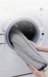Close-up of machine washable gray plush bathroom mat being placed in a washer