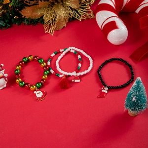 Christmas beaded bracelets with Santa and reindeer charms on festive red background