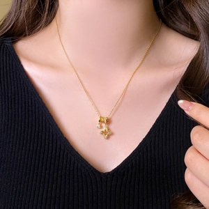 Détail d'un collier pendentif trèfle doré avec petits diamants sur le cou d'un mannequin