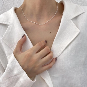 Close-up of a minimalist 925 sterling silver twisted chain necklace on a model