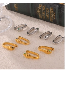 Macro shot of gold and silver snake earrings with emerald eyes on a vintage book