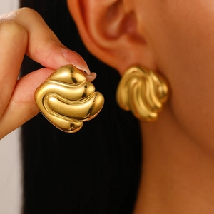 Detail of vintage 18K gold plated earrings featuring wavy fan-shaped textures on ears