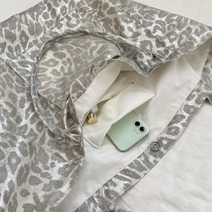Detail of silver leopard print tote bag interior showing canvas lining and zip pocket