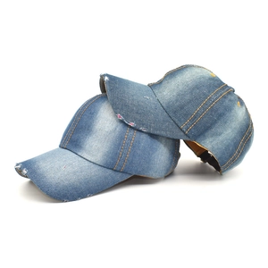 Detail of distressed denim baseball caps with orange stitching and ripped brim details