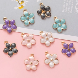 Detailed flat lay of ten colorful enamel flower charms with gold edges for DIY jewelry making