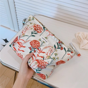 Detailed embroidery of red flowers and green leaves on a canvas toiletry bag