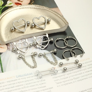 7-pair set of stainless steel nipple rings with heart and devil designs on gold tray