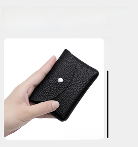 Detail of compact black pebble leather coin pouch with silver snap button in hand