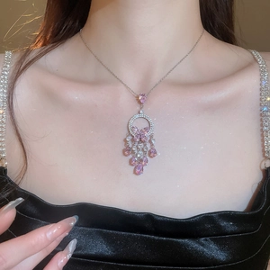 Detail of a silver necklace featuring pink gemstone butterfly fringe on a female model