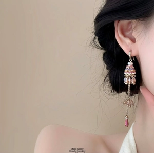 Détail de boucles d'oreilles à pompons avec cristaux roses et violets sur mannequin