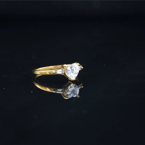 Minimalist gold heart-shaped moissanite ring with side diamonds on reflective black surface