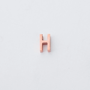 Detail van een gepolijste roségouden letter H kraal voor DIY sieraden met een klein gat van 1,8 mm
