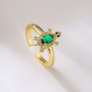Macro shot of gold-plated turtle ring with green gemstone and white zircon details