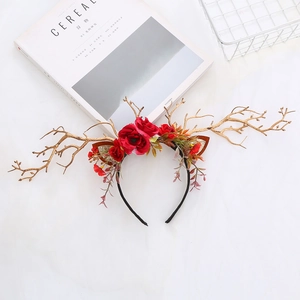 Close-up of golden reindeer antlers hairband with red velvet roses and berries