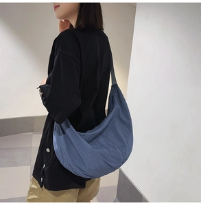 Détail du sac dumpling en nylon bleu porté par le modèle montrant sa grande capacité