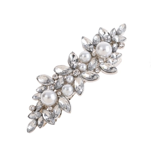 Detail of elegant gold hair clip with sparkling rhinestones and white pearls on a white background