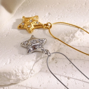Detail of gold and silver star necklaces with sparkling crystals on a stone surface