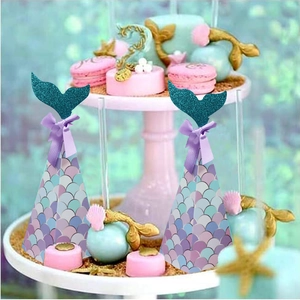 Mermaid party favor boxes with sparkling glitter fishtail and purple ribbon on a dessert stand