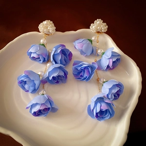 Macro di nappe di rose in tessuto blu e nuvola di perle bianche su ceramica bianca