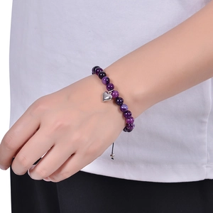 Bracelet en perles de jaspe zébré rose avec pendentif coeur au poignet d'une femme