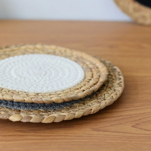 Stack of woven round heat resistant cotton rope and seagrass placemats on wooden table