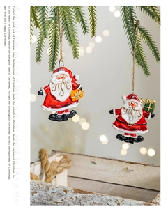 Detailed view of two vintage Santa Claus resin ornaments hanging on a pine branch