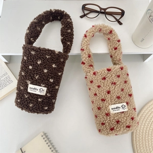 Close-up of plush heart-patterned cup carriers in brown and beige with soft faux fur texture