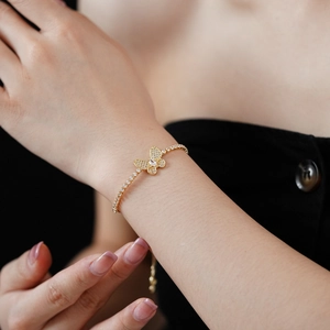 Gros plan d'un bracelet papillon doré avec zircons micro-pavés sur un poignet
