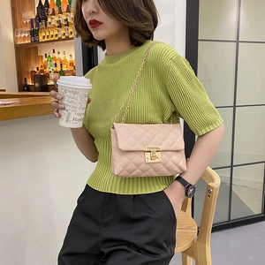Elegant beige quilted crossbody bag with gold chain strap shown on fashion model