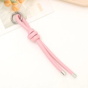 Geflochtener rosa PU-Leder-Schlüsselanhänger mit Silberring auf weißem Schreibtisch