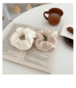 Close-up of soft faux rabbit fur hair scrunchies set in beige and white on a book