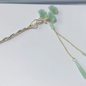 Macro detail of golden ginkgo leaf hair pin with green jade-like petals and tassels