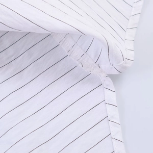 Detailed macro view of the side slit and fine stitching on the striped cotton shirt