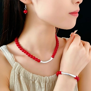 Gros plan sur un ensemble de bijoux ethniques en perles rouges portés par un mannequin